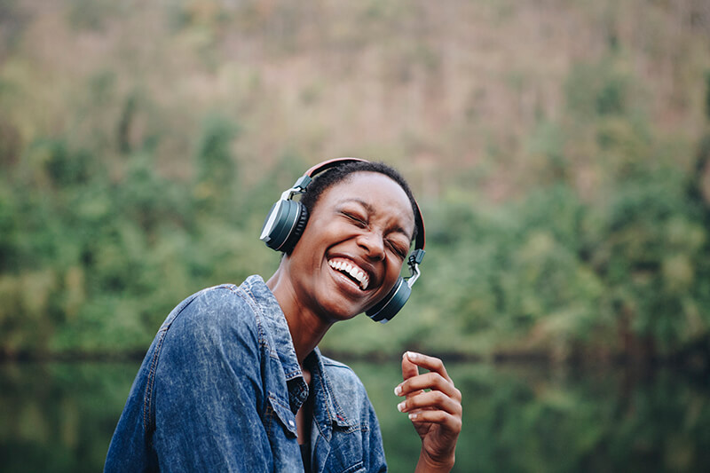 Woman listening to podcast with big earphones, laughing